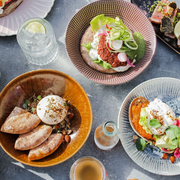 Bovenaanzicht van borden met kleurrijke dips, platbrood, witte kaas, salade en glazen bij Strandpaviljoen De Strandzot