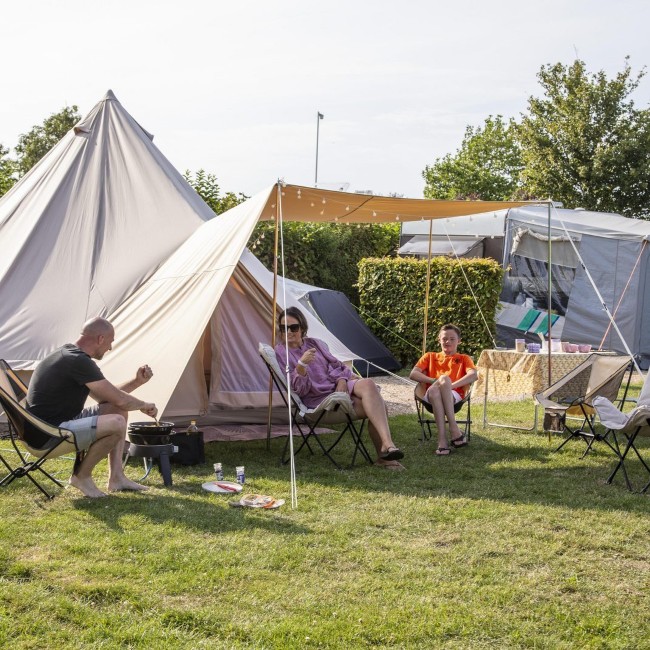 gezin ontspant bij glampingtent op camping zonneweelde