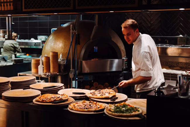 pizzabakker bereidt verse houtovenpizza bij piazza nieuwvliet