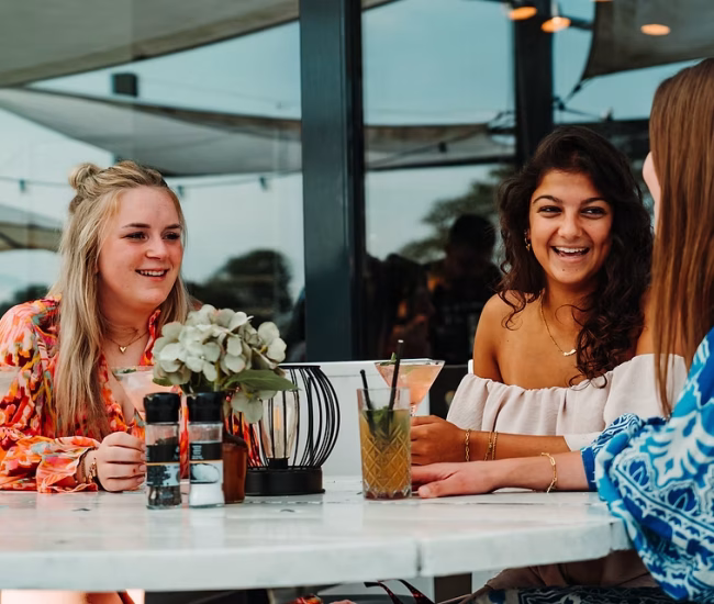 vriendinnen genieten van drankjes op het terras van piazza